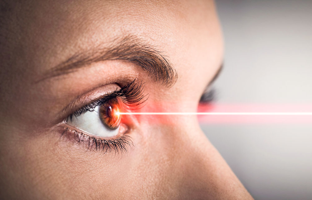 Weibliches Auge, auf welches ein roter Laserstrahl trifft