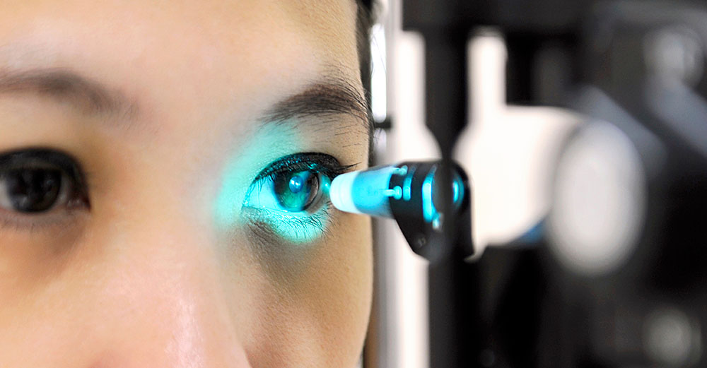 Tonometriekopf wirft blaues Licht auf ein weibliches Auges