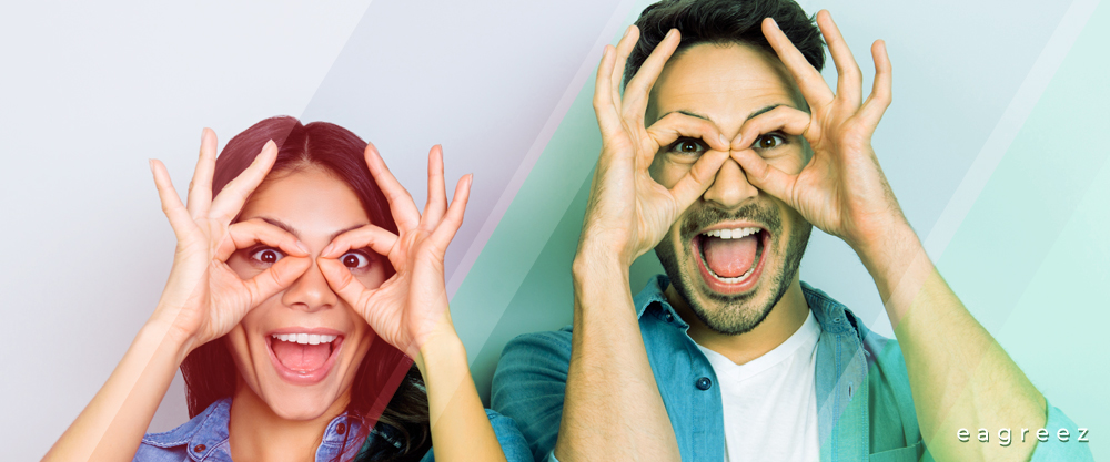 Frau und Mann mit Rot-Grün-Schwäche formen mit ihren Fingern Brillengläser und lächeln
